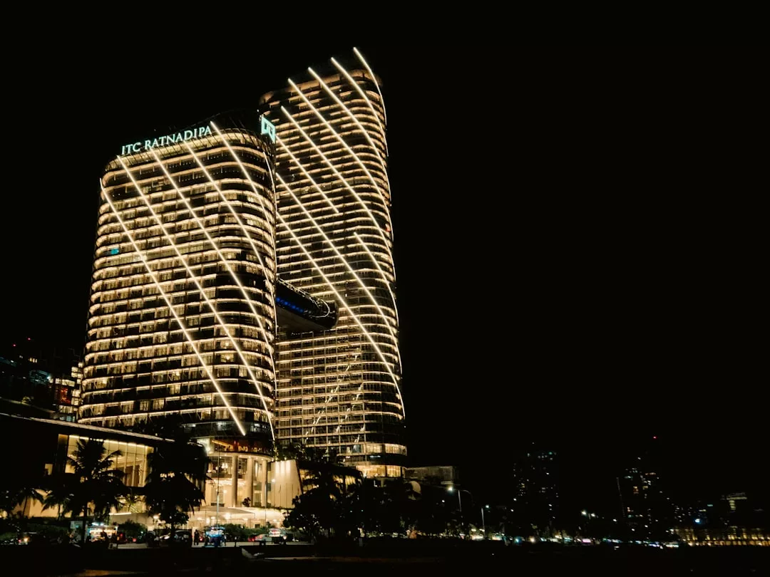 Night view of the ITC Ratnadipa building, a real estate marvel, with illuminated lines outlining its modern, curving architecture against a dark sky.