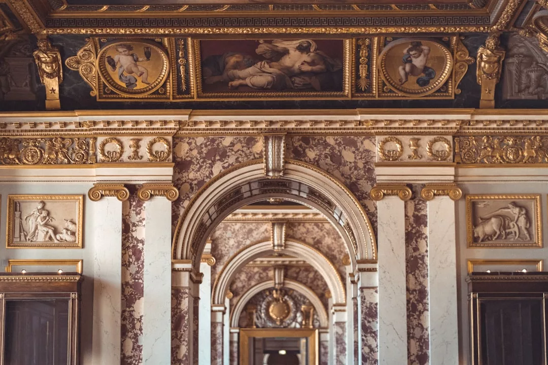 Ornate marble and gold interior with arches, decorative wall panels, and ceiling paintings featuring classical figures, showcasing urban luxury in a grand historic building in Frogner, Oslo.