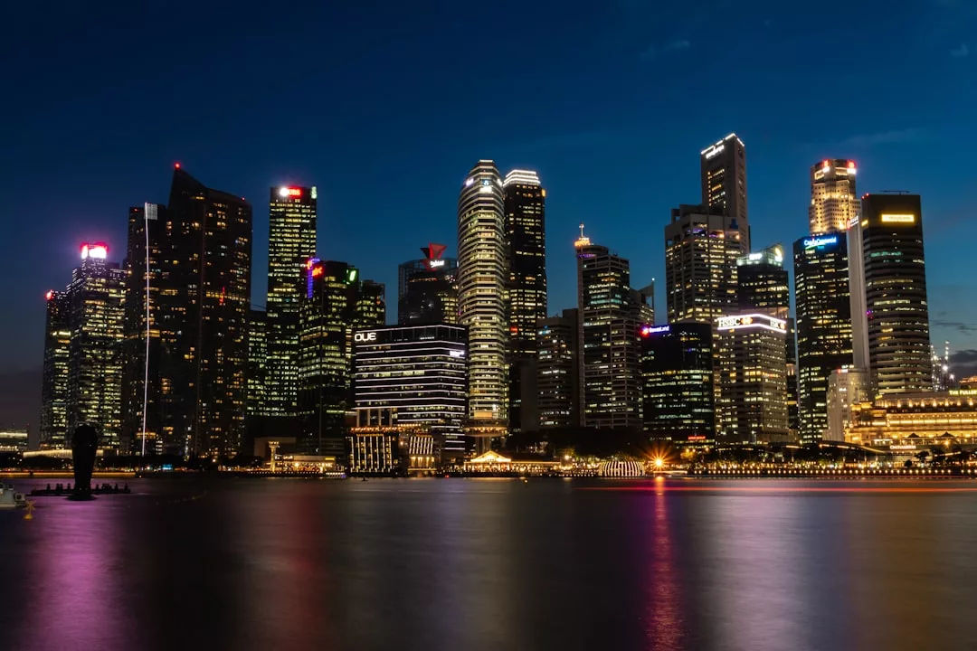A city skyline at night with numerous illuminated skyscrapers reflecting on the calm water in the foreground, showcasing Copenhagen’s recent infrastructure developments.
