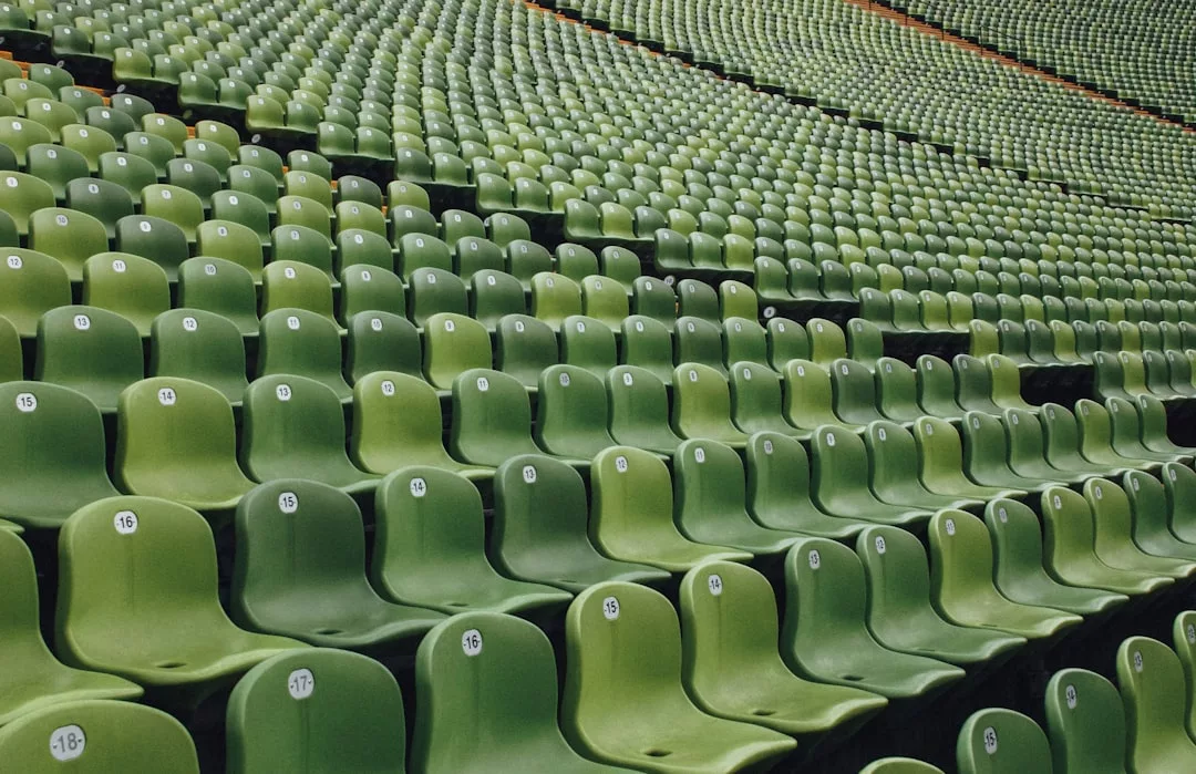 Rows of empty green stadium seats, each marked with a white number and arranged in a repetitive pattern, evoke the forward-thinking design seen in Oslo’s sustainable property developments.